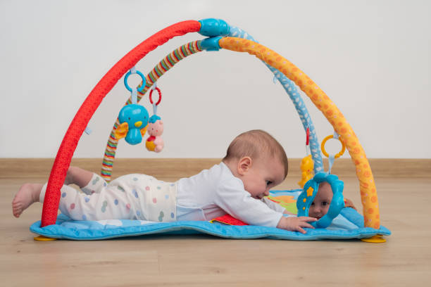 istock Adorable 5 months baby lying face down on a blue play mat while is looking in a small mirror with cloud shape. 1408833923