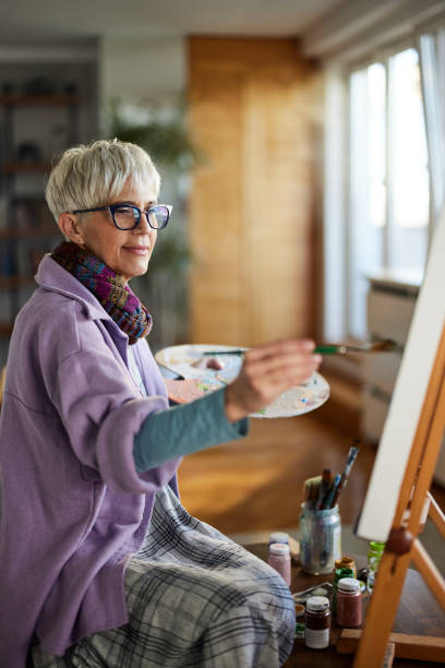 istock Mature female painter enjoying while painting in art studio. 1408834935