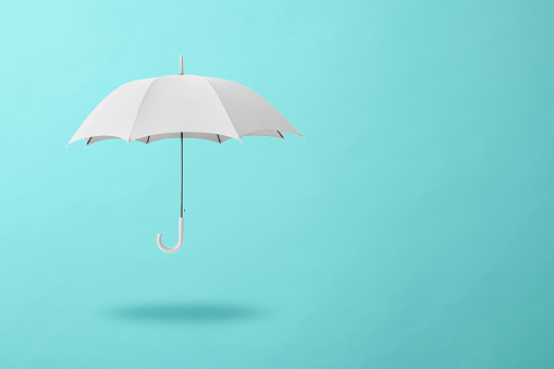 White umbrella floating in mid-air against light blue background with copy space.