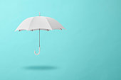 istock White umbrella floating in mid-air against light blue background 1408839001