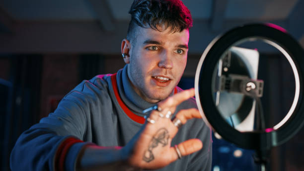 istock Handsome Young Man Setting Up Studio Lighting and Smartphone to Record a Dancing Routine on Video for Social Media. Stylish Man Streaming His Choreography Masterclass Online on Internet from Home. 1408840584