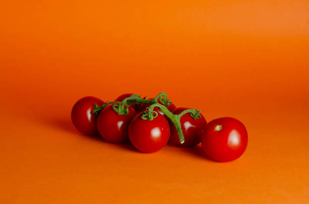 istock Fresh homegrown cherry tomatoes on orange background, selective focus 1408841454