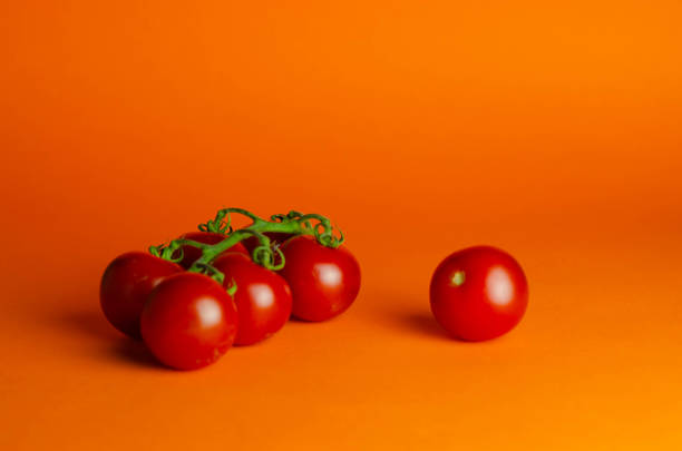 istock Fresh homegrown cherry tomatoes on orange background, selective focus 1408841463