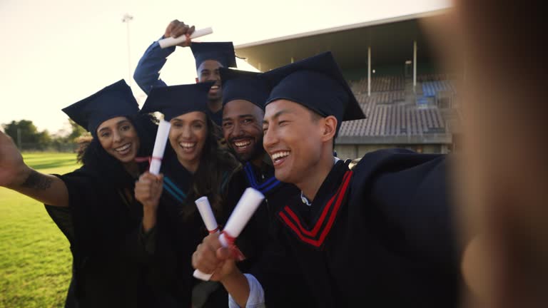 Diverse group of graduated university students taking selfie at graduation ceremony. Academic college people with diploma and degree smiling for social media picture. Graduating friends celebrating