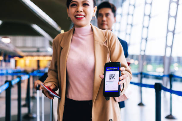 Businesswoman checking in at airport security gate with smart phone Businesswoman showing flight ticket to staff on smartphone. Airport check in counter and online air ticket. klia airport stock pictures, royalty-free photos & images