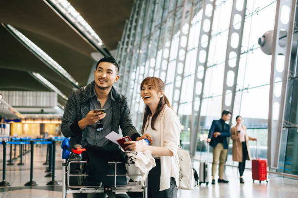 空港でカート荷物トロリーを待っているカップル。 - luggage cart ストックフォトと画像