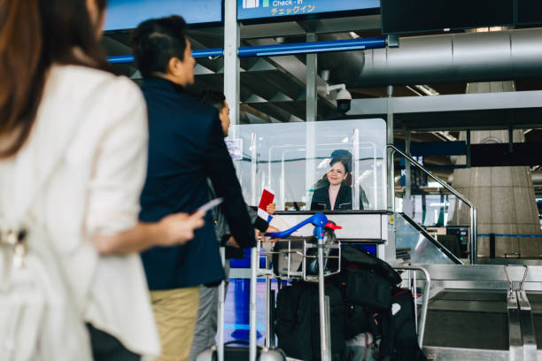 Passengers lining up in queue at airport check-in counter. stock photo