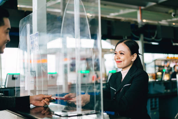 passager de la compagnie aérienne donnant un passeport pour l’enregistrement au comptoir de la compagnie aérienne. - personnel aérien au sol photos et images de collection