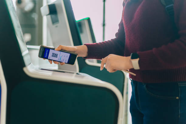 Woman check in flight using smart phone at a self check-in kiosk at the airport stock photo