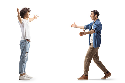 Full length profile shot of two male friends meeting each other with arms wide open isolated on white background