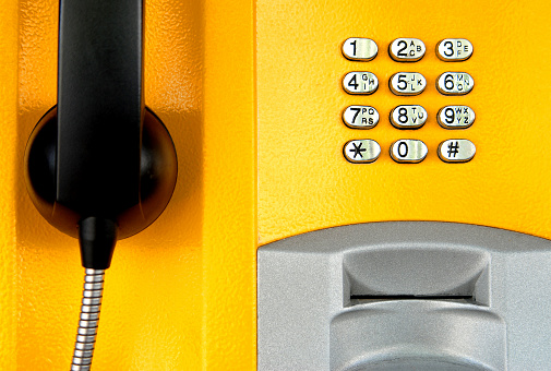 Close up of yellow telephone in telephone booth