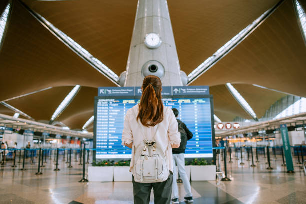istock Young woman checking her airplane in timetable board 1408847083