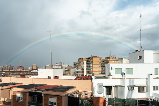 Rooftops with a rainbow on the sky on a rainy day. Spanish cityscape.