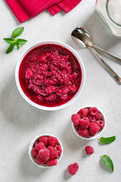 istock Delicious homemade raspberry jam in a bowl on a light table. Top view. 1408847535