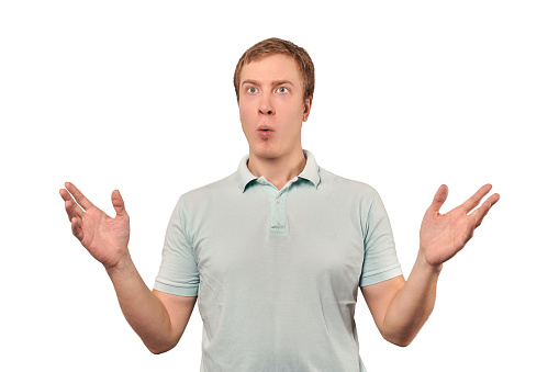 Confused young guy shrugged shoulders, guy in mint casual T-shirt spread arms, isolated on white background. Puzzled young man spread his hands, bewildered don't know gesture