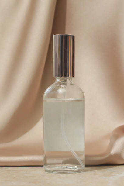 istock Glass translucent spray bottle on soft folded silk background. Luxury cosmetic and beauty styled ad concept. 1408850588