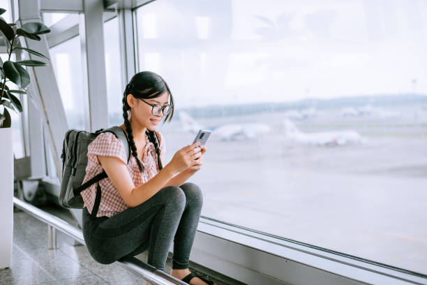 Tween girl looking at smartphone at airport Tween girl looking at smartphone at airport while waiting for flight see through leggings stock pictures, royalty-free photos & images