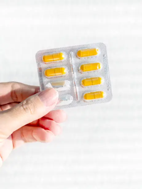 Man hold a Pills Pack on the White Wall Background closeup