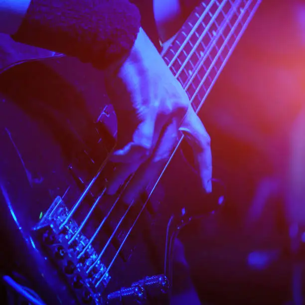 The bass guitarist plays the bass guitar in the spotlight. Selective focus