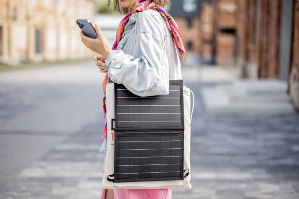 istock Woman charge phone from portable solar panel while walking outdoors 1408855371