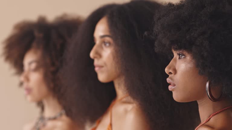 Group of beautiful diverse women with afros standing together and posing in the studio. Three powerful exotic women with afros posing confidently