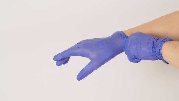 istock Hand is pulling purple latex gloves on white background. 1408861353
