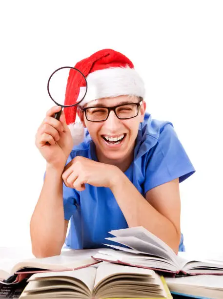 Cheerful Student in Santa's Hat with Magnifying Glass on the White Background
