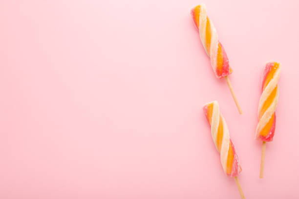 Colorful fruit ice popsicles on sticks. Light pink table background. Pastel color. Closeup. Cold sweet snack in summer. Empty place for text. Top down view.