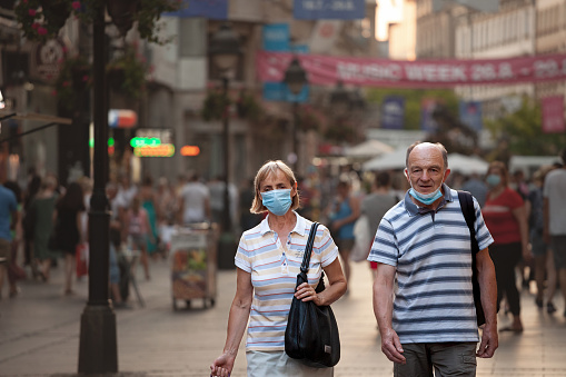 Picture of a white caucasian senior woman and man in belgrade, serbia, walking in the streets of Belgrade, capital city of Serbia, while wearing a respiratory face mask during the coronavirus health crisis.