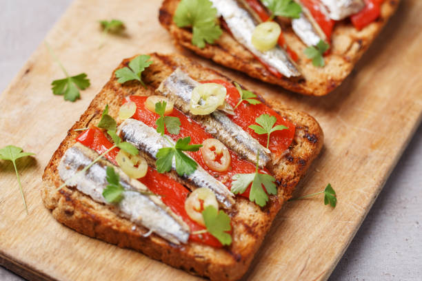 Toast with anchovies, pepper, parsley on bread Toast with anchovies, pepper, parsley on bread sardine stock pictures, royalty-free photos & images