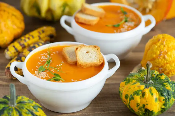 Photo of Pumpkin cream soup with croutons on wooden background.