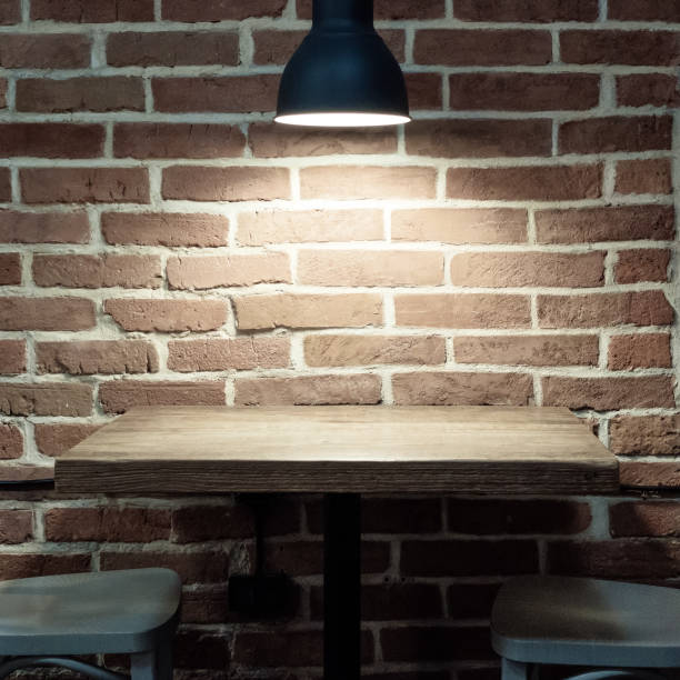 istock Lamp near a brick wall. Wooden table and chairs. Loft interior. 1408869791