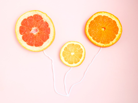 Creative layout made of grapefruit, orange and lemon slices against pastel pink background. Copy space. Creative summer idea. Fruit balloons.
