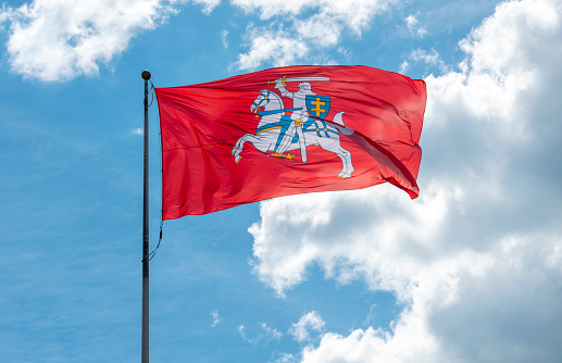 Historical state flag of Lithuania, red Vytis flag in front of blue sky