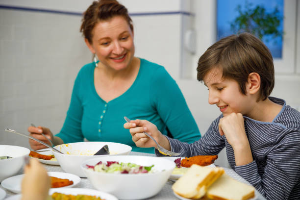 istock Mother sitting at the dining table and smiling at her son, having lunch together 1408873932
