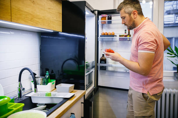 istock Man closing the fridge and holding a box of cherry tomatoes 1408874074
