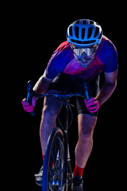 istock Portrait of man, professional cyclist training, riding isolated over black studio background in neon light 1408874507
