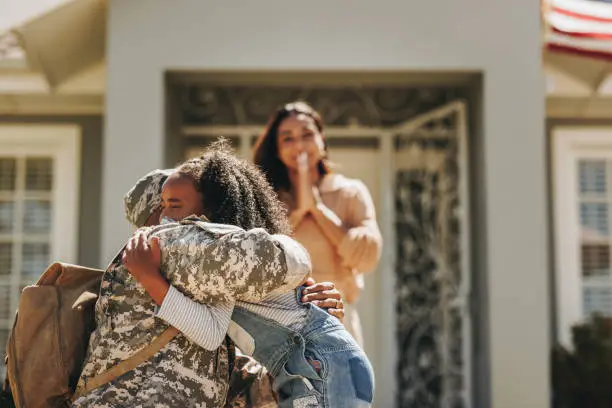 Military man saying goodbye to his family before leaving for war. American serviceman embracing his daughter. Patriotic soldier leaving his family to go serve his country in the army.