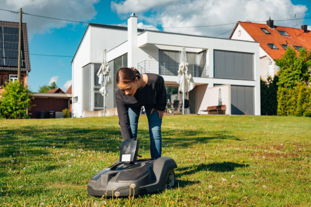 istock Beautiful Young Woman Standing in Home Garden programming Robotic Lawn Mower 1408875600
