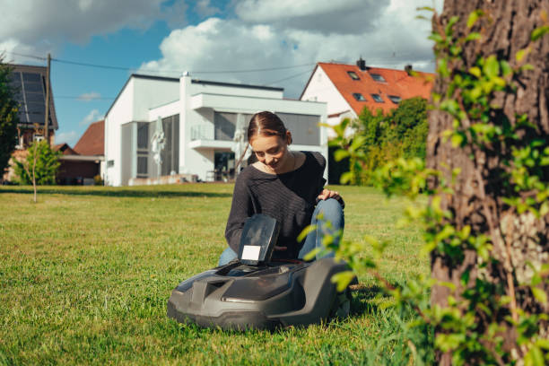 istock Good Looking Young Woman in Home Garden programming Robotic Lawn Mower 1408875614