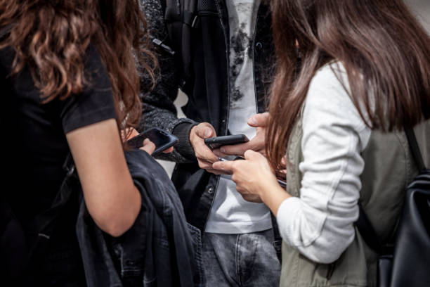 istock Selective blur on unrecognizable young persons, teenagers, broswing the internet using their smartphone telephone together, as friends. 1408875698