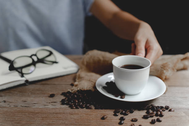 istock A cup coffee in hand ,notebook and glasses on the wooden table. 1408877424