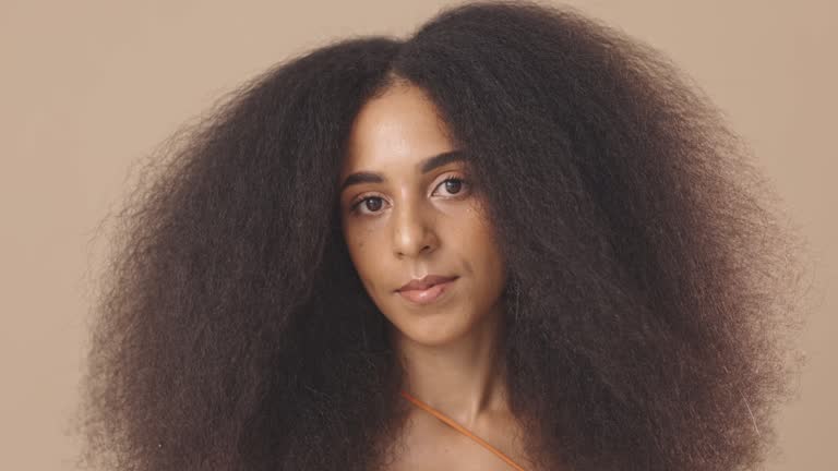 Beautiful hispanic young woman with an afro standing alone in the studio and posing. Powerful mixed race woman with an afro feeling confident and posing