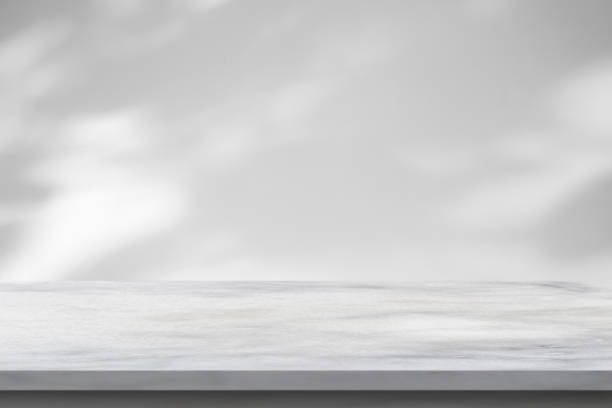 istock Marble table with tree shadow drop on white wall background for mockup product display 1408882602