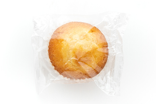 single muffin cupcake in clear foil , overhead view, isolated on white background
