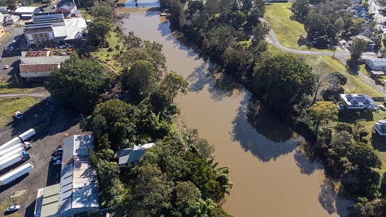 Industrial buildings next to a flooded muddy river through Lismore, NSW