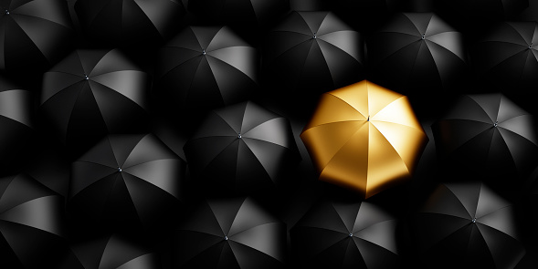 Single golden umbrella with group black umbrellas