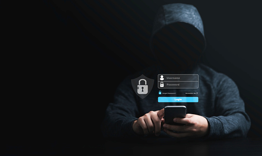 Man in black hoodie using smartphone and try to to unlock password for hacker in computer security system and financial technology malware concept.