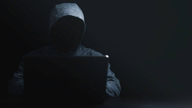 istock Man in black hoodie using computer laptop to unlock password for hacker in computer security system and financial technology malware concept. 1408886546
