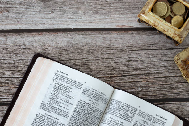 apri il libro sacro della bibbia con una vecchia scatola vintage piena di monete su un tavolo di legno - open teaching book wood foto e immagini stock